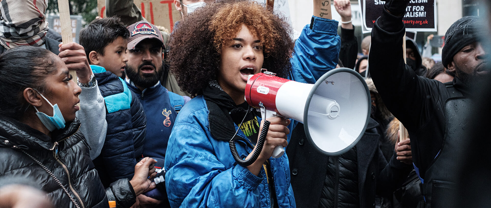 A woman with curly hair is holding a megaphone.