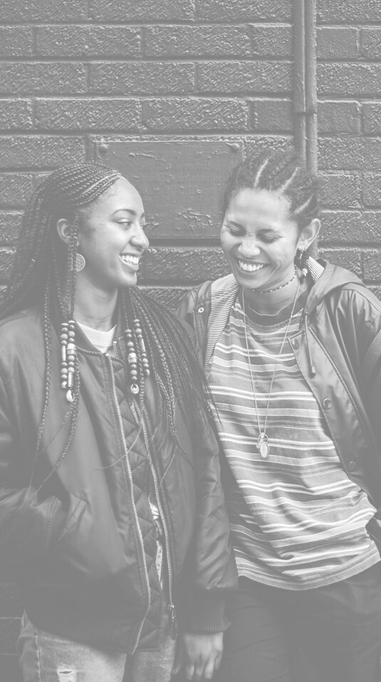 Two women are smiling and laughing together.