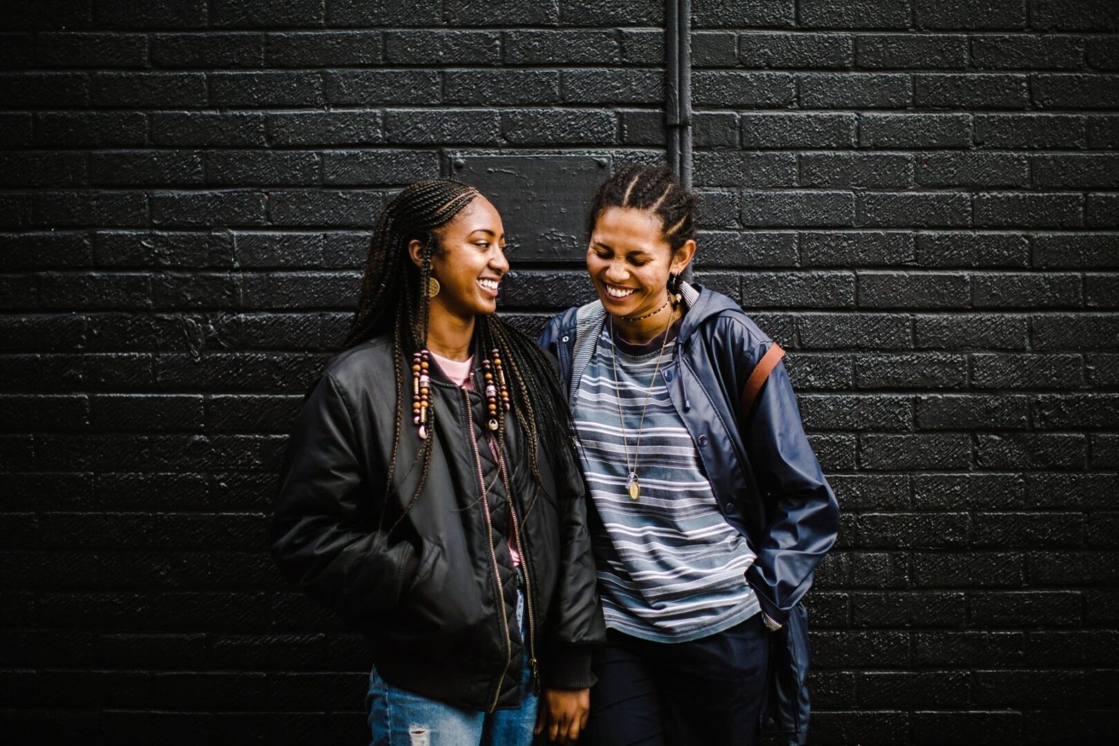 Two women standing next to each other near a wall.