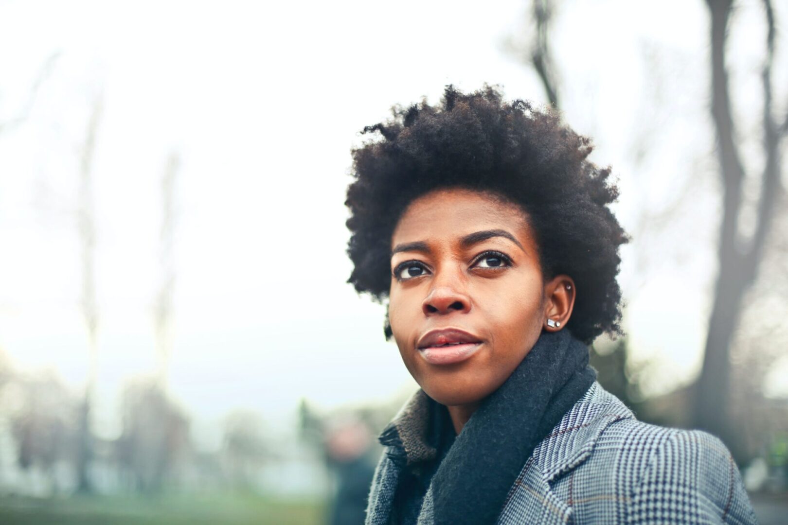 A woman with short hair is standing outside.