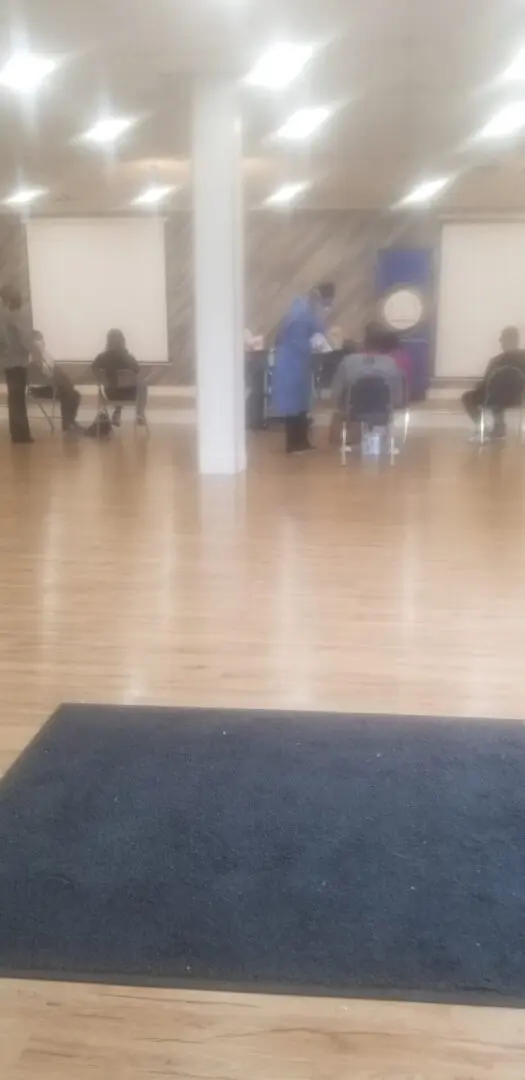 A group of people sitting on the floor in an empty room.